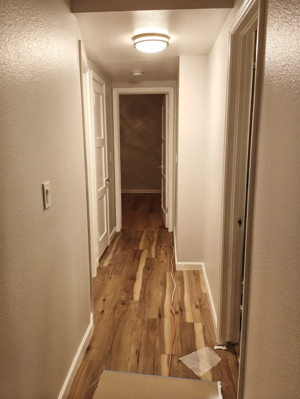 Wood-look flooring and white trim along a narrow hallway